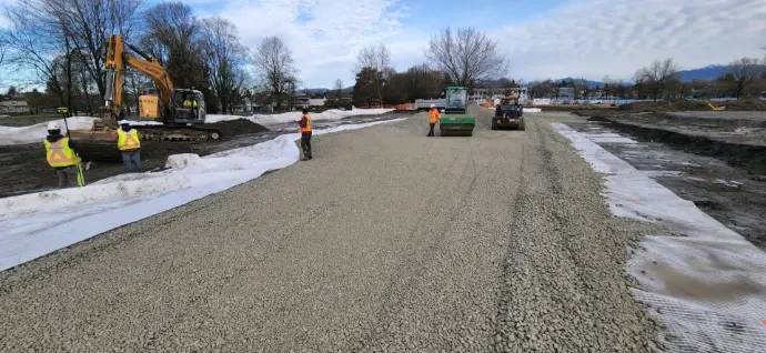 Crew and roller working along a long strip of compacted foam glass aggregate fill